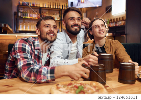Front view. Soccer fans. Three friends are in the bar drinking beer and having a good time Front view. Soccer fans. Three friends are in the bar drinking beer and having a good time 124651611
