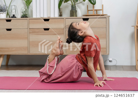Yoga Practice and Flexibility. A child performs a yoga pose at home, showcasing flexibility and concentration. 124651637