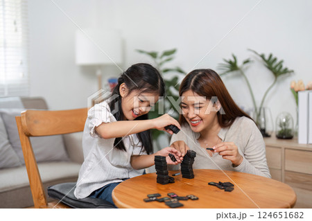 Family Fun and Interaction. Engaging in a lively domino game, a mother shares joyful moments with her daughter. 124651682