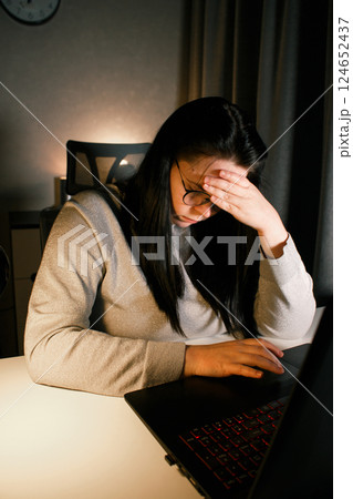 Tired woman working on computer touching her head because of headache. Office worker with migraine. Stressed overworked employee suffering from pain on workplace. 124652437