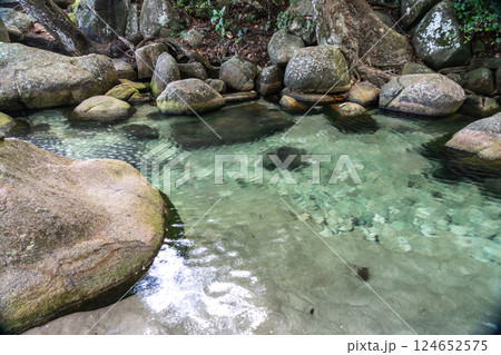 Crystal-clear stream pool surrounded by mossy boulders and tropical forest Crystal-clear stream pool surrounded by mossy boulders and tropical forest 124652575
