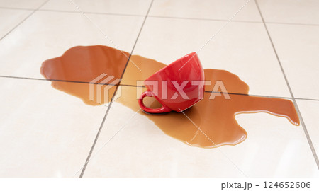 Spilled coffee, coffe puddle stain on tiled floor, messy leak with fallen cup, brown drink spillage 124652606
