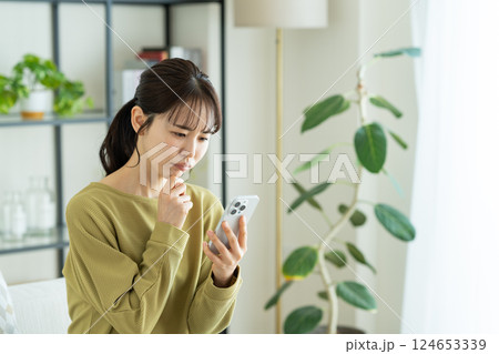 リビングでスマホを使う若い女性 124653339
