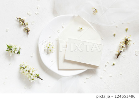 Card and envelope on plate near tulle and wild plums white flowers top view, romantic wedding mockup 124653496