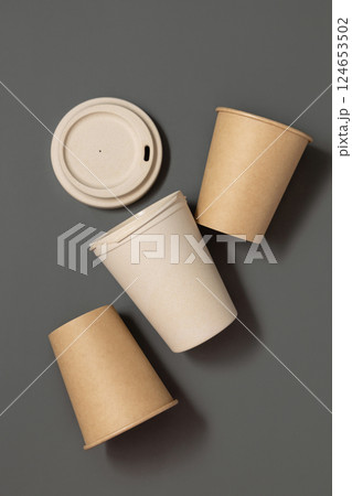 New beige kraft paper cups and reusable bamboo coffee cup on a gray top view, mockup 124653502