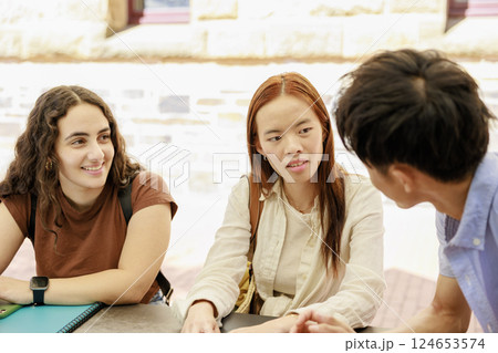 屋外のキャンパスで談笑する大学生の男女 124653574