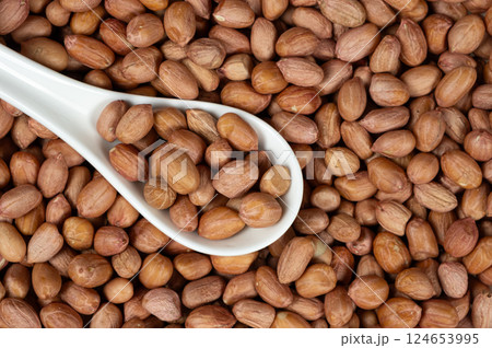 Raw peanut kernels in brown peel in a spoon close-up. Raw peanut kernels in brown peel in a spoon close-up. 124653995