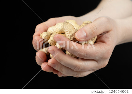 Handful of unpeeled whole peanuts in hands, close-up. Handful of unpeeled whole peanuts in hands, close-up. 124654001