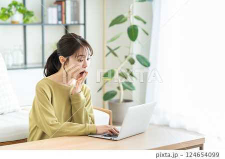 リビングでパソコンを使う若い女性 リビングでパソコンを使う若い女性 124654099