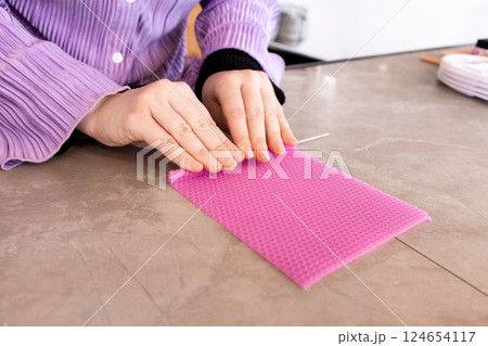 Female crafting beeswax candle with pink sheet on marble table 124654117