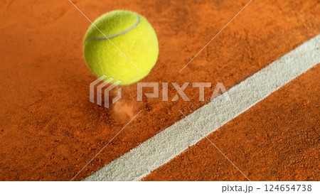 Freeze Motion Detail Shot of Tennis Ball Hitting a Clay Court 124654738