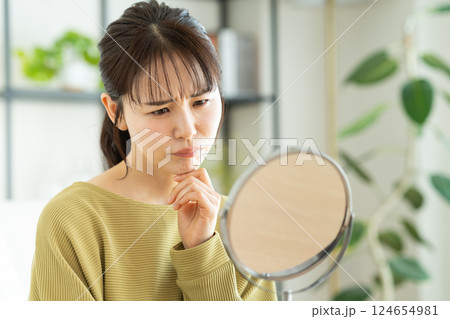 リビングで鏡を見る若い女性のビューティ リビングで鏡を見る若い女性のビューティ 124654981