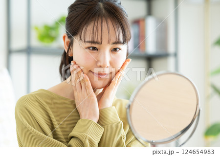 リビングで鏡を見る若い女性のビューティ 124654983