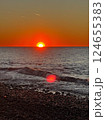 Vibrant sunset over ocean with waves washing onto pebble beach 124655383