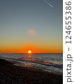 Sunset over pebble beach with ocean waves and sky contrails 124655386