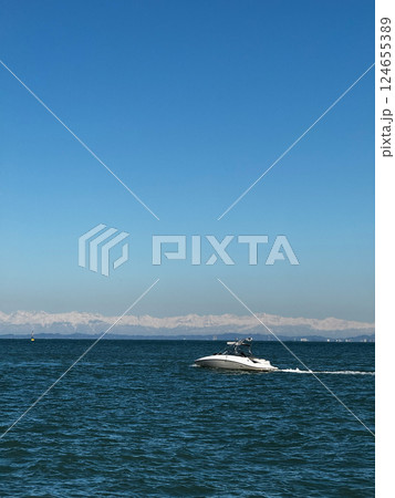 Speedboat on Deep Blue Ocean with Snowy Mountains in Background 124655389