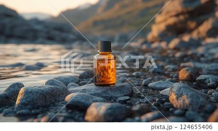 A bottle of face serum with amber liquid, lying on top of rocks.  124655406