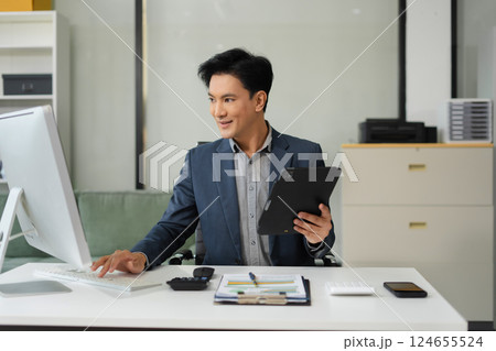 Businessman working at office with tablet and laptop computer and papers on desk. Businessman working at office with tablet and laptop computer and papers on desk. 124655524