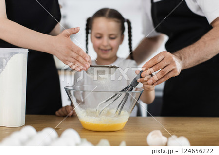 Caucasian family in kitchen cooking together. Parents and child prepare batter using whisk. Caucasian family in kitchen cooking together. Parents and child prepare batter using whisk. 124656222