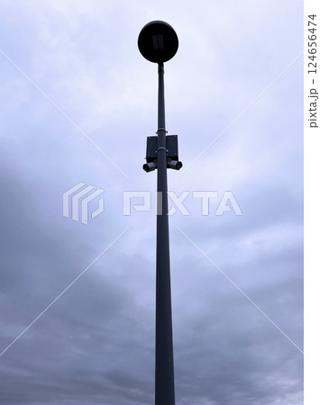 Streetlight against grey, overcast sky. The tall lamp post is central in the image, with a cloudy background, emphasizing urban infrastructure and atmospheric conditions 124656474
