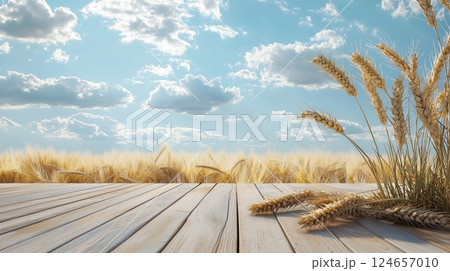 There are two golden wheat ears on the wooden floor, with a wheat field and blue sky.  There are two golden wheat ears on the wooden floor, with a wheat field and blue sky.  124657010