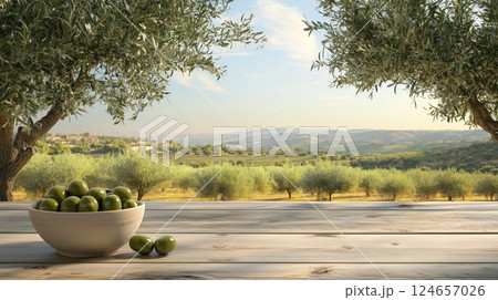 An olive grove on a sunny day, with a table with a bowl of green olives.  124657026