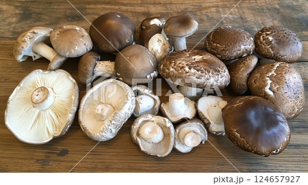Assorted fresh mushrooms laid out on a wooden table.  124657927