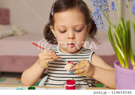 Little child girl paint Easter eggs at home. kid is preparing for Easter. Little child girl paint Easter eggs at home. kid is preparing for Easter. 124658540