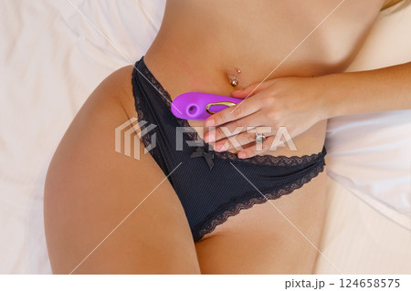 Young woman holding sex toy dildo vibrator in bed 124658575