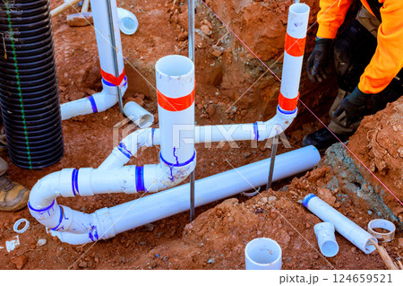 Workers laying out PVC wastewater pipes for an underground drainage system in freshly dug trench. Workers laying out PVC wastewater pipes for an underground drainage system in freshly dug trench. 124659521