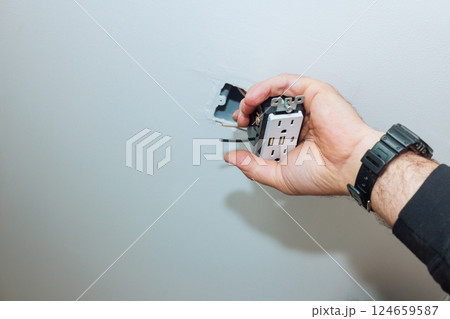 Electrician works on installing new outlet with USB ports in home interior during renovation works 124659587