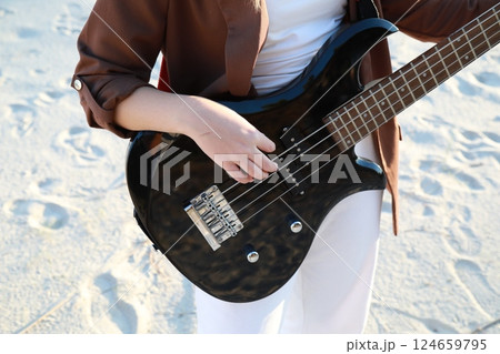 Girl Plays Bass Music Instrument On The Beach At Sunset Near Ocean Girl Plays Bass Music Instrument On The Beach At Sunset Near Ocean 124659795