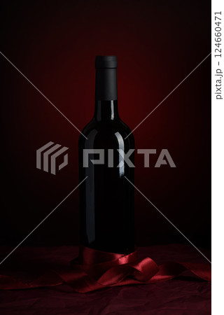 Bottle of red wine on dark red background. Front view 124660471