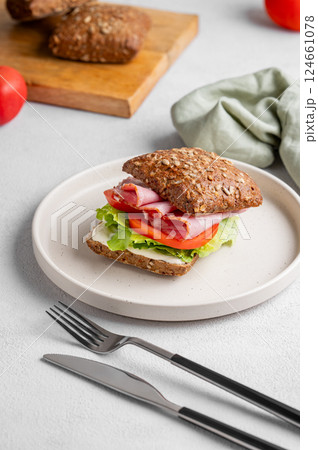Toast club sandwich made of grain bread with prosciutto, cheese, tomatoes, lettuce and sauce 124661078