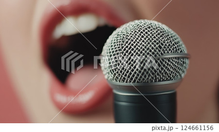 Close up of a singer's vibrant red lips passionately singing into a microphone, encapsulating the dynamic energy of live performance and the art of musical expression 124661156