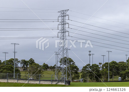A large Transmission Tower running through a grassy field 124661326