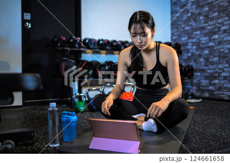 タブレットでYouTube動画を見ながらジムで運動するかっこいい女性 ストレッチ やり方 動画視聴 タブレットでYouTube動画を見ながらジムで運動するかっこいい女性 ストレッチ やり方 動画視聴 124661658