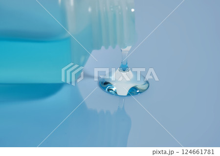 Shampoo pouring out of a small tube on a blue background. Texture. Shampoo pouring out of a small tube on a blue background. Texture. 124661781