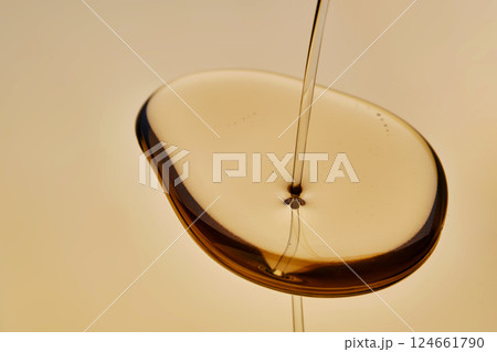 Texture of pouring cosmetic oil on a golden background. 124661790