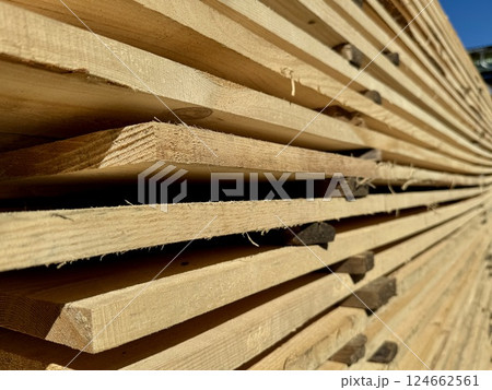 Stacked Wooden Planks Sunlit in Lumberyard 124662561