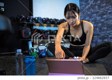 タブレットでYouTube動画を見ながらジムで運動するかっこいい女性　ストレッチ　やり方　動画視聴 124662657