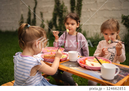 Three children enjoy a colorful meal outdoors on a sunny day Three children enjoy a colorful meal outdoors on a sunny day 124662851