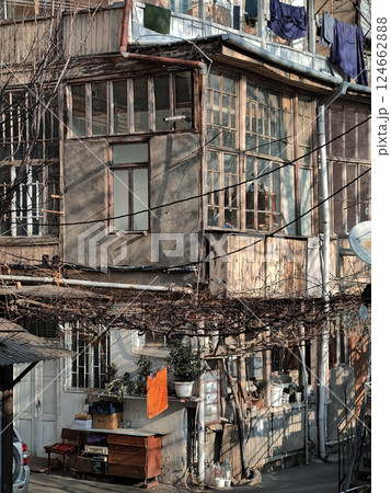A close-up view of a rustic residential building with peeling paint, wooden windows, and clothes hanging outside. The image captures urban authenticity and daily life. 124662888