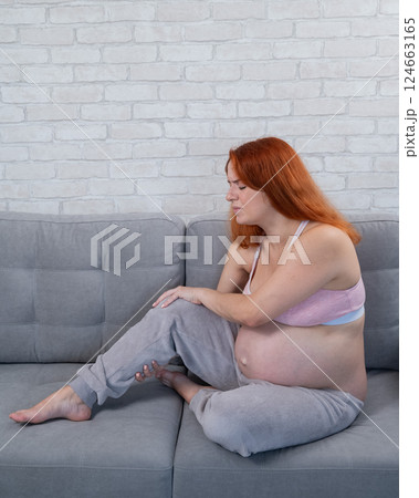 Caucasian pregnant woman suffering from leg cramps. Third trimester. Caucasian pregnant woman suffering from leg cramps. Third trimester. 124663165