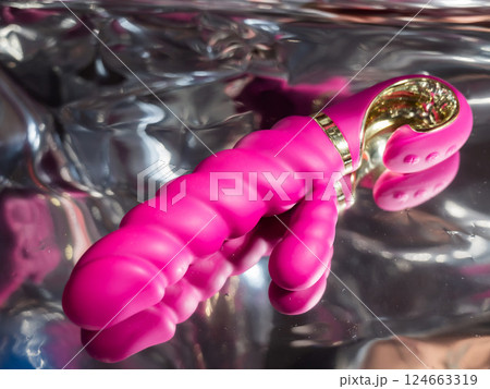Sex toy on a metal background in the reflections of light.  124663319