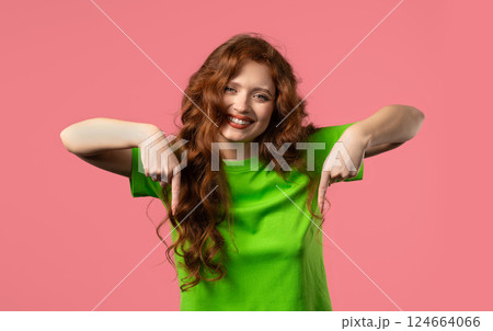 Charming woman pointing down advertising area. Pink background. Click subscribe 124664066