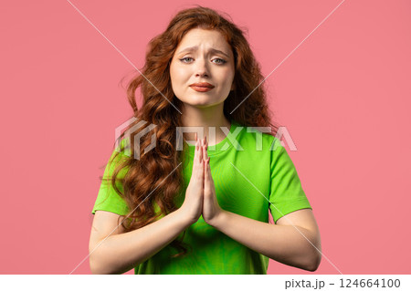 Woman praying, begs to apologize, she guilty. pink background. Hopeful prayer. 124664100