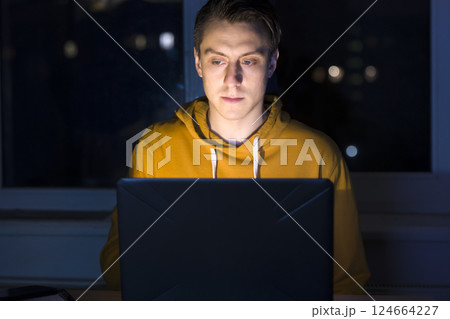 Man is working on a laptop at night. 124664227