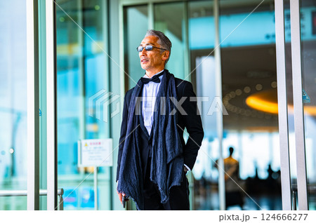 施設の自動ドアから屋外に出てくるタキシードを着た紳士 施設の自動ドアから屋外に出てくるタキシードを着た紳士 124666277