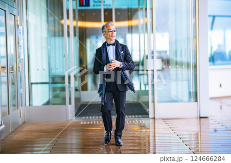 施設の自動ドアから屋外に出てくるタキシードを着た紳士 124666284